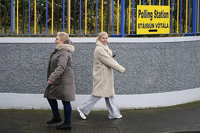 A person walks to a polling station as another person walks in the opposite direction