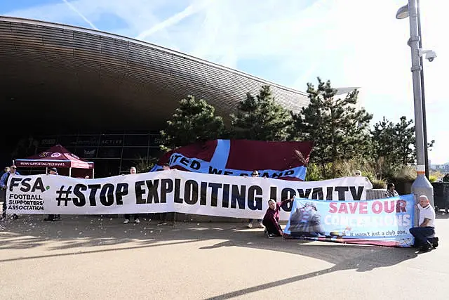 Fans hold up an FSA banner reading “Stop Exploiting Loyalty”