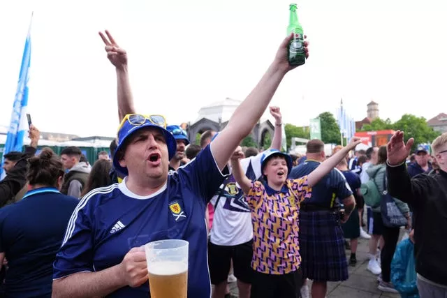 Scotland fans in Stuttgart hold up beer bottles