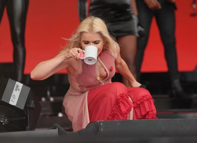 Paloma Faith drinks from a mug while performing on stage