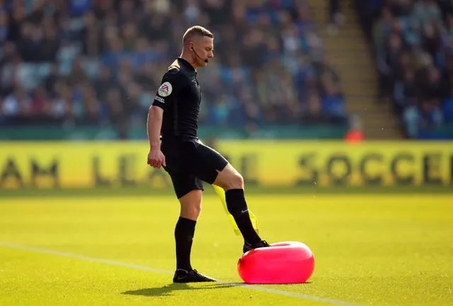 Assistant referee Wade Smith bursts a balloon thrown onto the pitch
