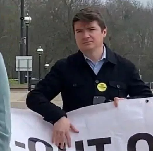 Former Sinn Fein press officer Michael McMonagle holding a banner