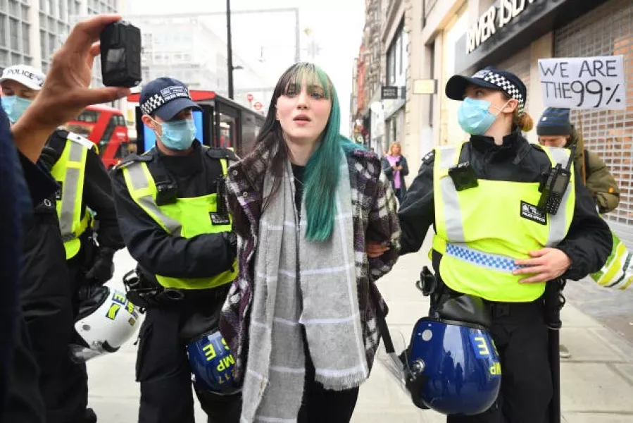 Police detain a woman during an anti-lockdown protest at Oxford Circus 