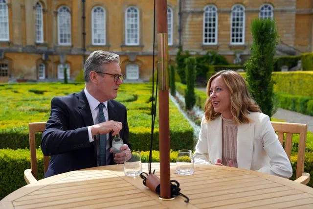 A man and a woman sit at a table in a garden