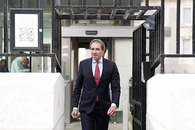 Simon Harris emerges as he walks up steps outside a building