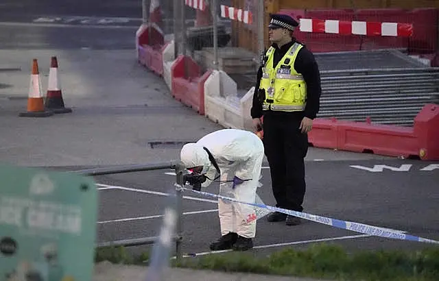 A forensic officer takes a photograph in a car park close to the car allegedly involved in an incident near the migrant processing centre in Dover, Kent, on Sunday