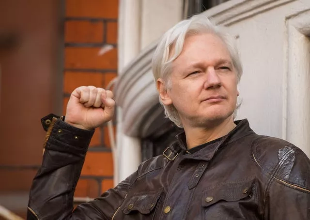 Julian Assange holds up a clenched fist as he speaks to the media at the Ecuadorian embassy in London
