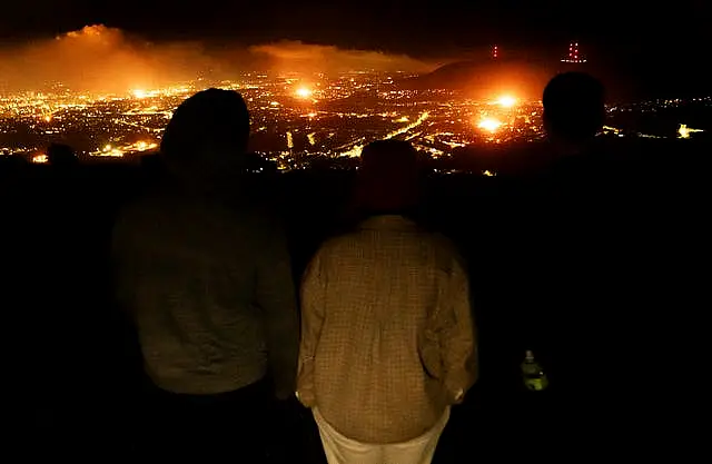 People looking out over Belfast as various bonfires burn