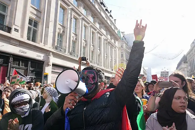 A masked supporter shouts through a megaphone during the march