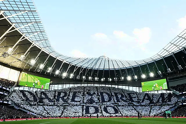 Tottenham fans in the stands hold up tiles that read “Dare Dream Do” in the stands