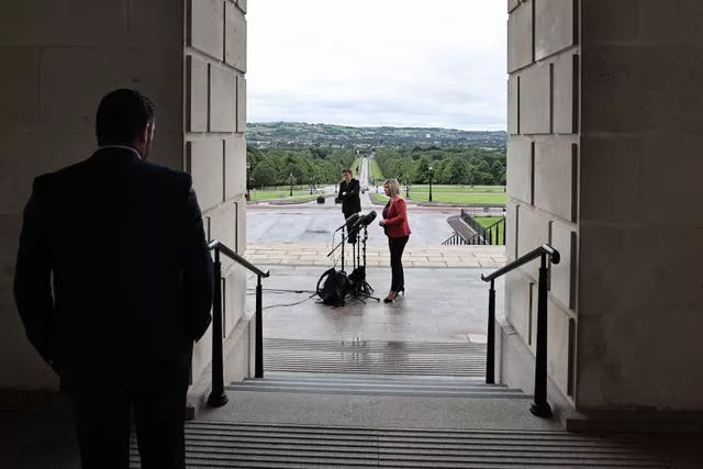 Sinn Fein press officer Sean Mag Uidhir looks on as Deputy First Minister Michelle O’Neill takes part in a press conference outside Parliament Buildings in Stormont, Belfast in 2020