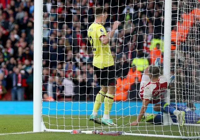 Arsenal’s Leandro Trossard falls into the goal post after scoring the opening goal