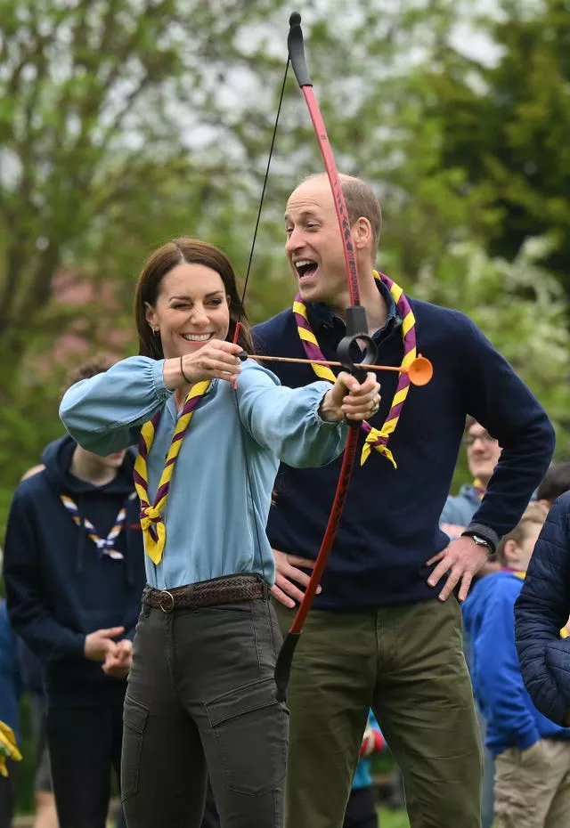 The Princess of Wales, watched by the Prince of Wales as she tries archery 