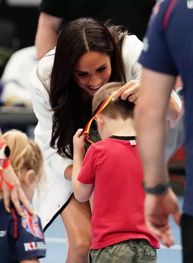 The Duchess of Sussex hands out medals to children on the basketball court at the Merkur Spiel-Arena during the Invictus Games in Dusseldorf, Germany. 