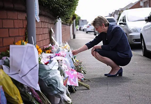 Home Secretary Yvette Cooper reads messages left on flowers