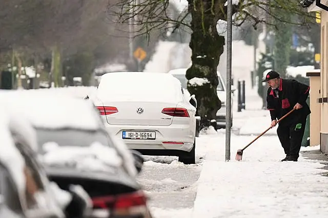 A man clears snow from the pavement in Ballylynan in County Laois