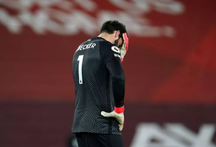 Liverpool goalkeeper Alisson Becker covers his face with his hand after making a mistake against Manchester City