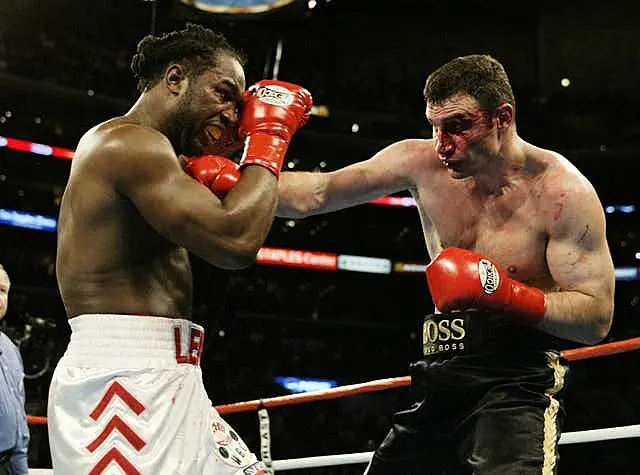 Vitali Klitschko, with a bloody face, punches Lennox Lewis