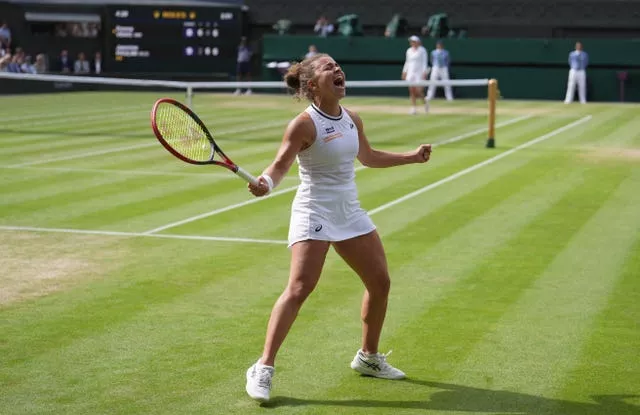 Jasmine Paolini roars in celebration and holds her arms out wide with the court behind her