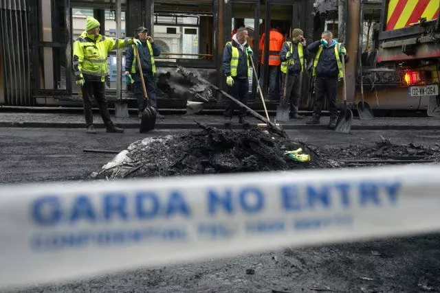 Debris is cleared from a burned out Luas and bus in O’Connell Street in Dublin in the aftermath of violent scenes in the city centre on Thursday evening