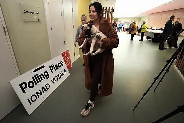 A woman walks down a corridor with her pet pug under her arm