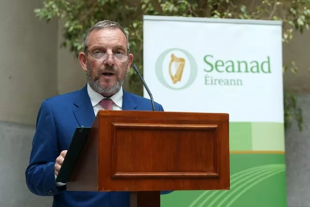 Senator Jerry Buttimer speaking from behind lectern with a Seanad Eireann sign next to him