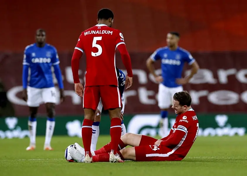 Liverpool captain Jordan Henderson sits on the pitch injured watched by Georginio Wijnaldum