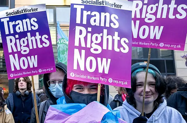 Campaigners holding up signs reading 'Trans rights now'