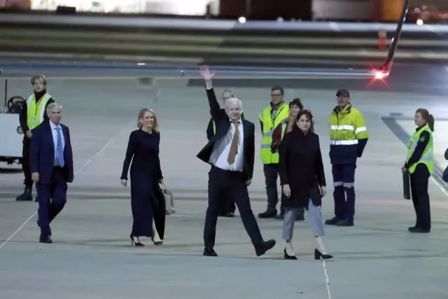 Julian Assange waves as he arrives at an airport in Canberra