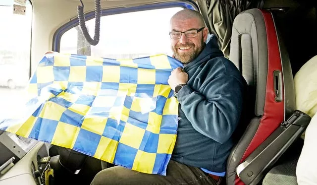 Truck driver Donal Lennon holds a flag in his cab as the Aid From Ireland lorries prepare to leave Dublin Port 