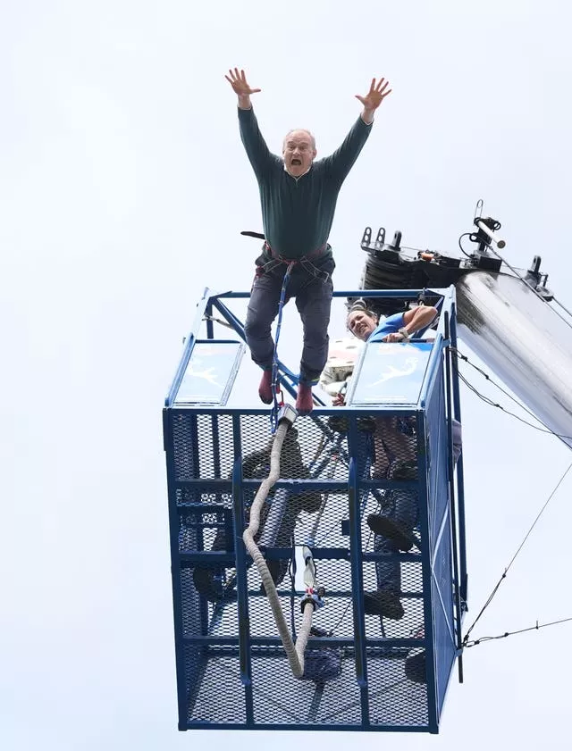 Sir Ed Davey diving from a platform for a bungee jump