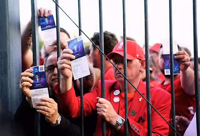 Liverpool fans show their tckets through a fence