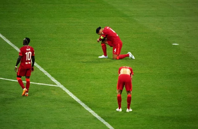 Liverpool defender Virgil Van Dijk kneels dejected on the pitch 