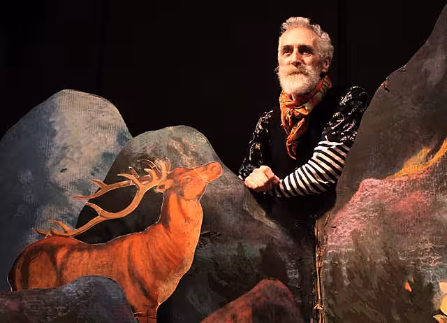 John Byrne standing behind an artwork