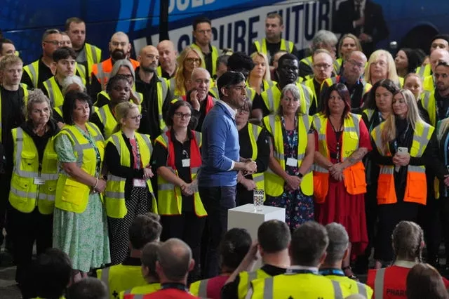 Rishi Sunak delivers a speech surrounded by workers in hi vis jackets