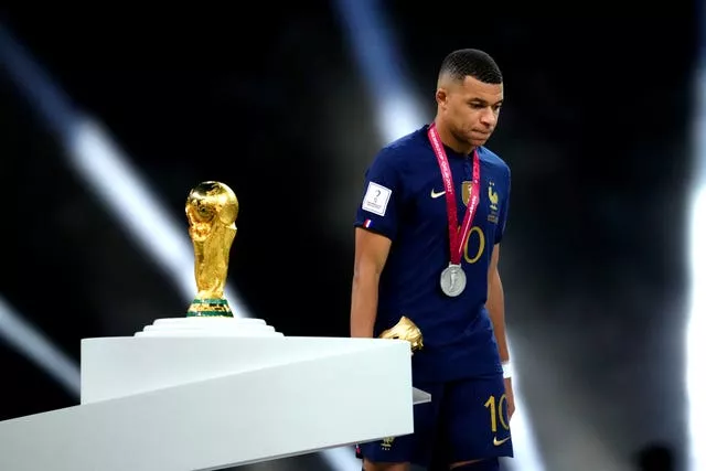 France’s Kylian Mbappe walks past the World Cup trophy
