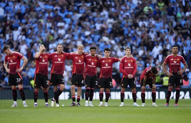 Manchester United players stand dejected on the halfway line during the penalty shootout