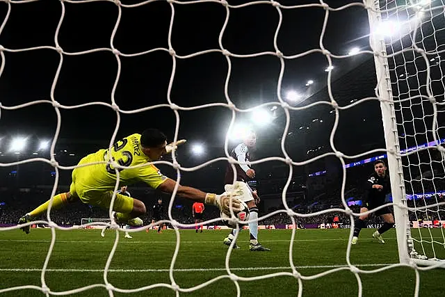 Aston Villa goalkeeper Emiliano Martinez dives low to his right to claw the ball off the line