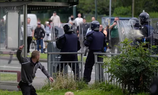 A protester throws an object at officers as they deploy pepper spray 