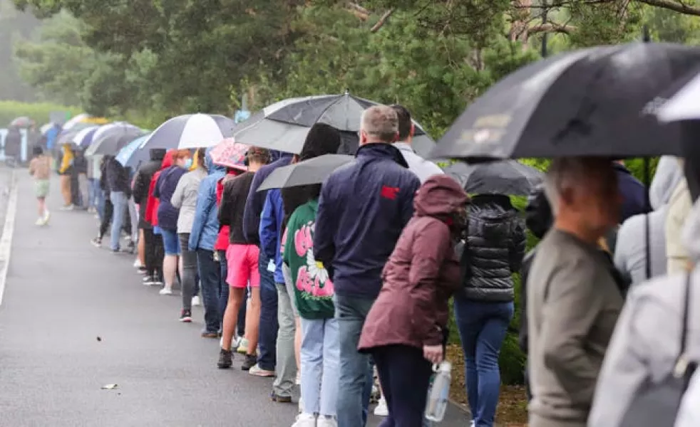 Parents and their children queue in the pouring rain outside the Citywest Covid-19 Vaccination Centre in Dublin (Damien Storan/AP)