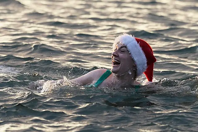 A woman with a Father Christmas hat swims in the sea