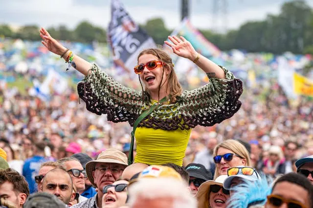 A person sways their arms as crowds watch Olivia Dean perform at Glastonbury