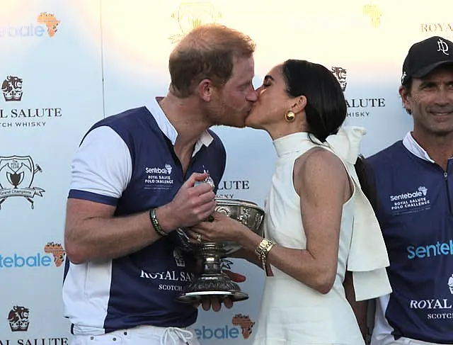 Harry and Meghan kiss on the podium during the trophy presentation at the Royal Salute Polo Challenge