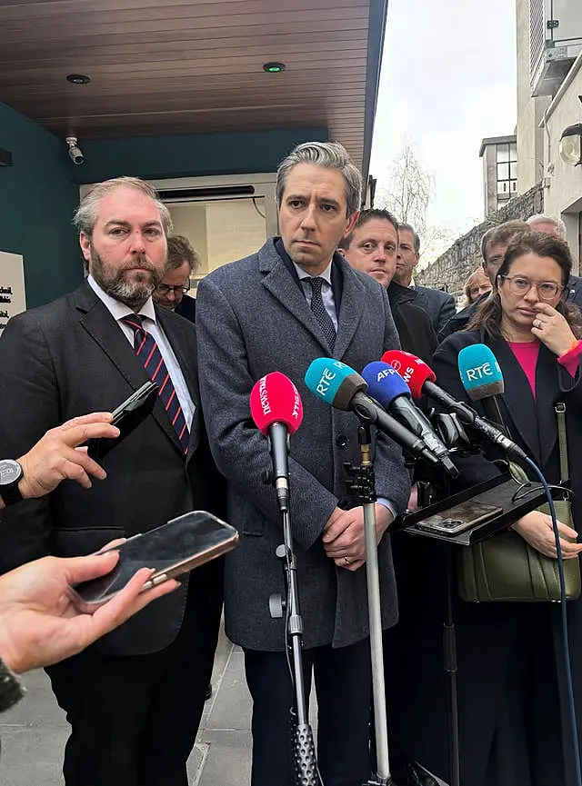 Simon Harris speaks into a number of microphones 