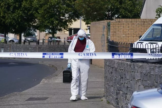 A forensics officer walking on road behind police tape