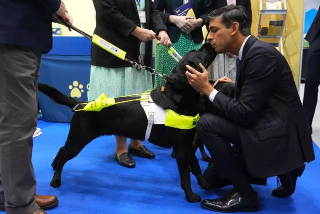 Prime Minister Rishi Sunak greets a guide dog as he tours the Exhibitor’s Hall at the Manchester Central convention complex, during the Conservative Party annual conference