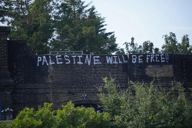 The words 'Palestine will be free' painted in white on a railway bridge.