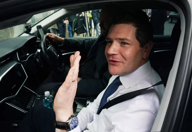 Minister for Enterprise Peter Burke waves while sitting in a car