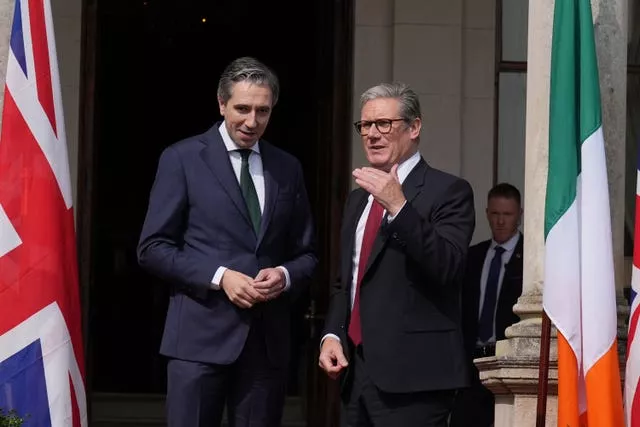 Simon Harris and Sir Keir Starmer standing between a Union and Irish flag outside Farmleigh House