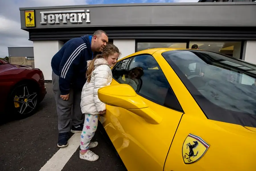 Neil Robinson and his daughter Miley look at Ferrari cars at the Charles Hurst dealership in Belfast (Liam McBurney/PA)